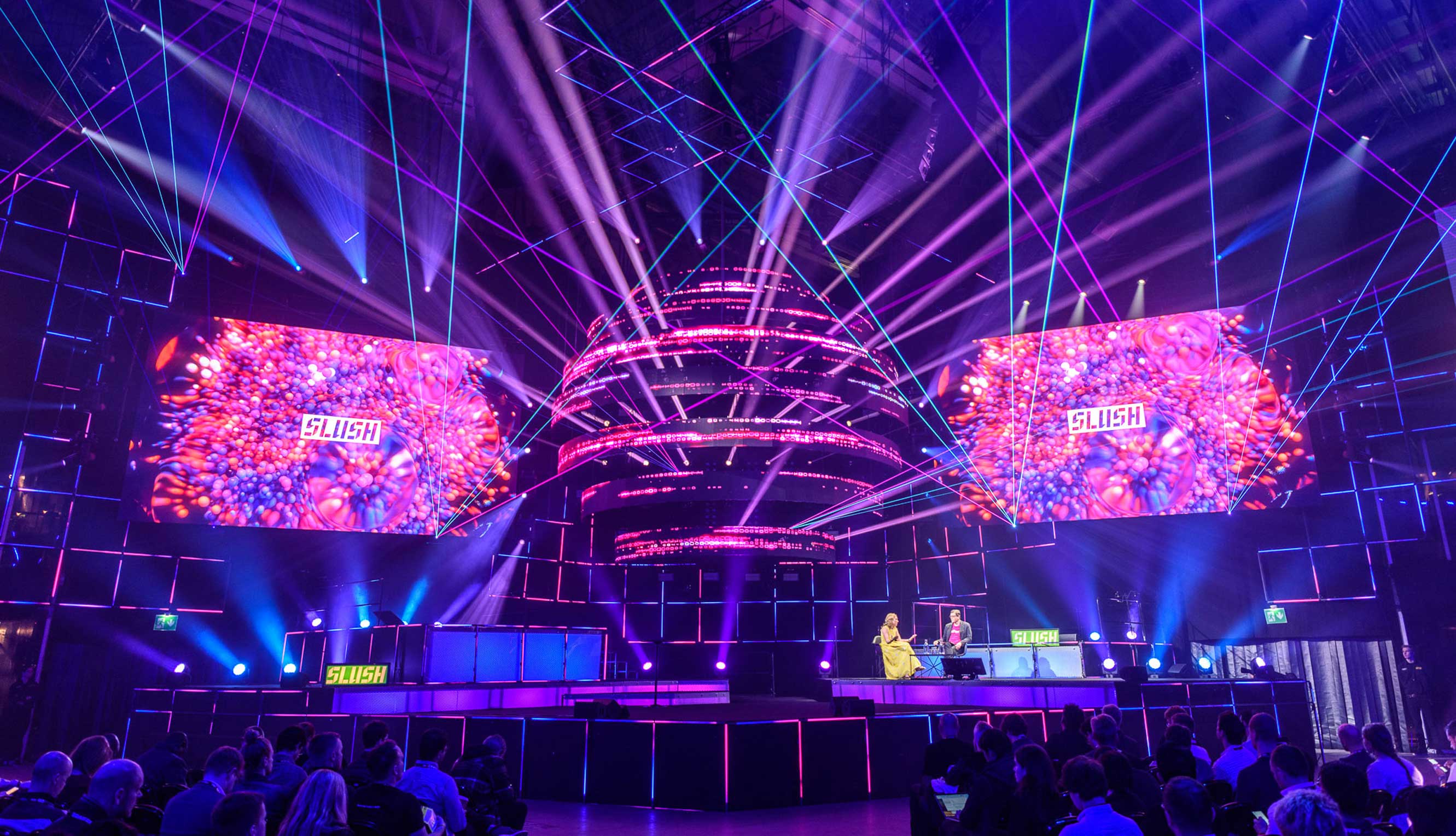 Slush stage lit with purple lasers, with ‘SLUSH’ on the side screens above the audience