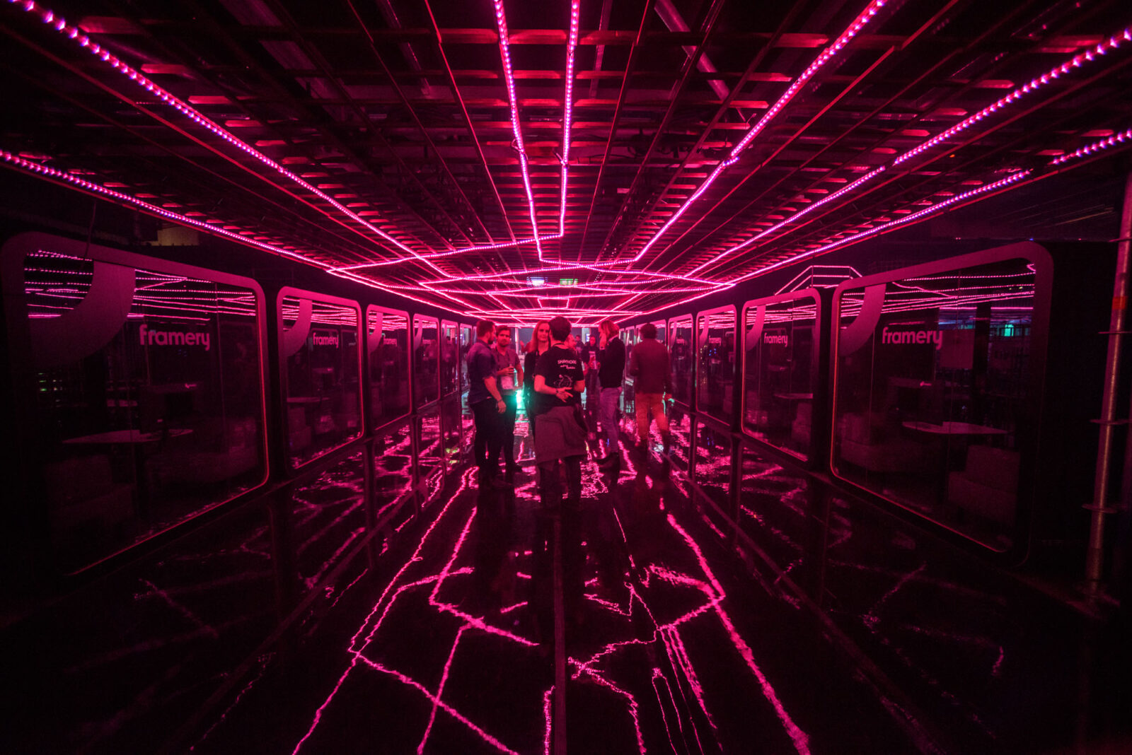 Corridor lined with pink neon light strips forming a glowing tunnel, with a reflective floor