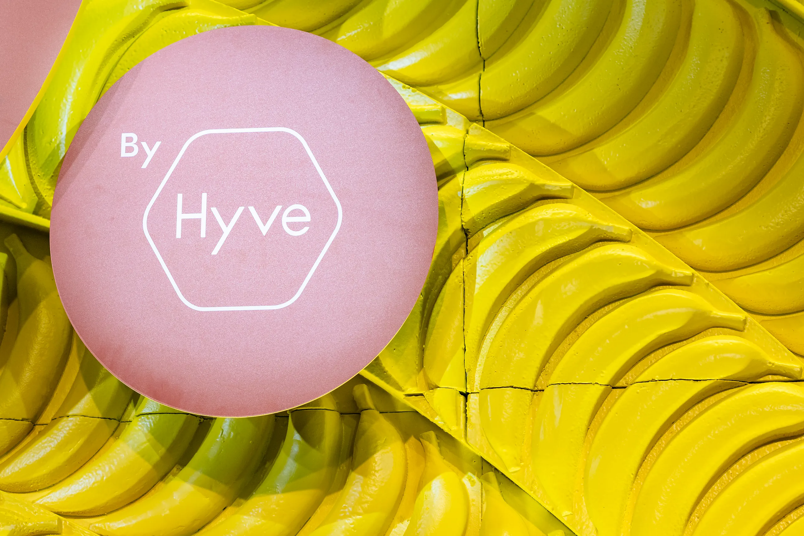 Close-up of a pink ‘By Hyve’ sphere against a stage backdrop built from rows of yellow bananas